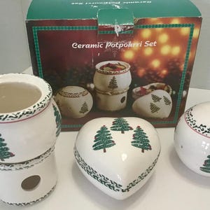 May include: A ceramic potpourri set with a box that reads "Ceramic Potpourri Set". The set includes a stackable pot, a heart-shaped container, and two round containers. Each piece is white with green Christmas tree designs.