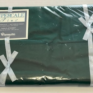 May include: A dark green twin flat sheet, wrapped in clear plastic and tied with light gray ribbons. The sheet has a label that reads "Supercale Plus" and "Twin Flat Sheet". The sheet is made of 60% cotton and 40% polyester.