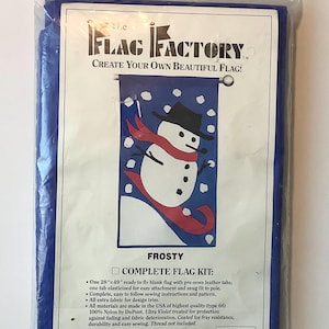 May include: A complete flag kit featuring a snowman design on a blue background. The kit includes a 28" x 49" blank flag with pre-sewn leather tabs, instructions, and extra fabric for trim. The flag is made in the USA of 100% nylon and is treated for protection against fading and fabric deterioration. The kit is from the Flag Factory and has a style number of 63734.