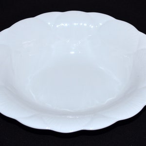 Könnte beinhalten: Eine weiße Keramikschüssel mit einem gewellten Rand. Die Schüssel ist leer und hat eine glatte, glänzende Oberfläche.