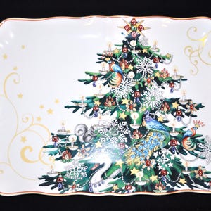 May include: A rectangular white ceramic serving tray with scalloped edges and a thin orange rim. The center features a detailed illustration of a green Christmas tree decorated with candles, snowflakes, a squirrel, and a colorful peacock.