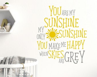 Peut inclure: Un autocollant mural de décoration pour chambre d'enfant avec le texte "You are my sunshine, my only sunshine, you make me happy when skies are grey". Le texte est en jaune et gris avec un graphique de soleil jaune.