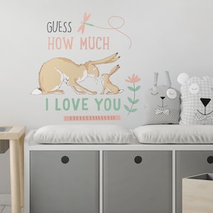 May include: A white storage bench with three drawers and a cushioned top. The bench has a gray fabric cushion and two gray and white patterned pillows. A wall decal with a bunny and the text "Guess how much I love you" is on the wall behind the bench.