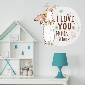 May include: A white wall with a round, cream-colored sticker featuring a cartoon bunny and the text "I love you to the moon and back".