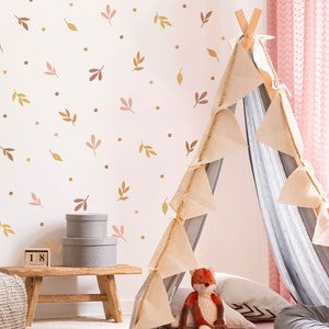 May include: A white wall with pink and brown leaf and dot decals. A teepee tent with a gray and white striped fabric interior is in the corner of the room. The teepee has a brown wooden frame and beige fabric flaps. A stuffed fox is sitting inside the teepee.