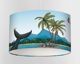 May include: A cylindrical lampshade featuring a whimsical island scene. The design includes a whale's tail, palm trees with a toucan and monkey, and a parrot. The background is a light blue sky and ocean with a small island.