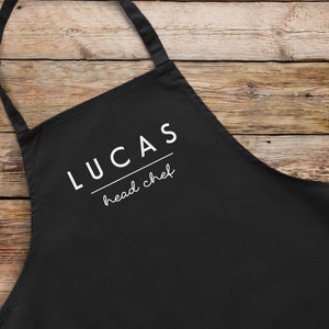 May include: Black apron with white text that reads "Lucas head chef".