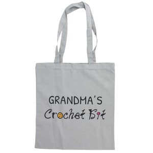 May include: A gray canvas tote bag with black text that reads "Grandma's Crochet Bit" with a small orange button and a pink button graphic.