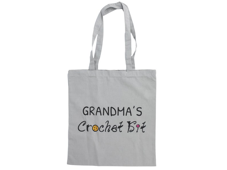 May include: A gray canvas tote bag with black text that reads "Grandma's Crochet Bit" with a small orange button and a pink button graphic.