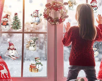 May include: A young person in a red sweater looks out a window decorated with snowman decals and a wreath. The window is framed in pink and overlooks a snowy scene. Snowflakes and a red and white plaid pattern are also visible.