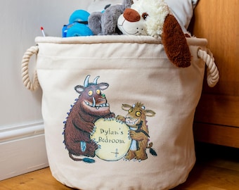 May include: A beige canvas storage bin with rope handles, filled with stuffed animals. The bin features a colorful illustration of two cartoon monsters holding a sign that reads "Dylan's Bedroom".