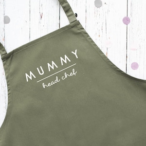 May include: A green apron with the text "MUMMY head chef" printed in white.
