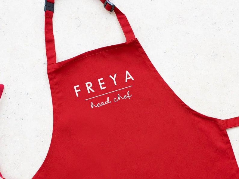 May include: Red apron with white text that says "FREYA head chef".