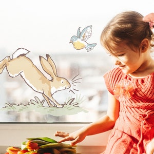 May include: A young girl in a red knitted dress looks at a window with a hand-drawn illustration of a rabbit jumping, a bird flying, and green grass.