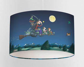May include: A cylindrical lampshade featuring a whimsical illustration of a witch flying on a broomstick at night. The witch is accompanied by a dog, a tiger, and other creatures. The background depicts a full moon, stars, and a landscape.