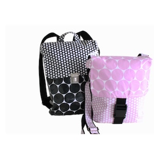 Könnte beinhalten: Zwei Taschen mit Polka-Dot-Muster. Eine ist ein schwarz-weißer Rucksack mit silbernem Verschluss. Die andere ist eine rosa-weiße Umhängetasche mit schwarzer Schnalle. Beide Taschen haben schwarze Riemen.