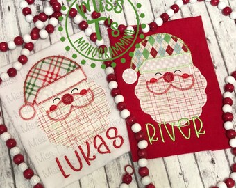May include: Two white and red shirts with embroidered Santa Claus faces and personalized names "Lukas" and "River".