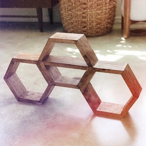 Puede incluir: Una estanter&iacute;a hexagonal de madera con tres niveles. La estanter&iacute;a est&aacute; hecha de madera natural con un acabado r&uacute;stico.