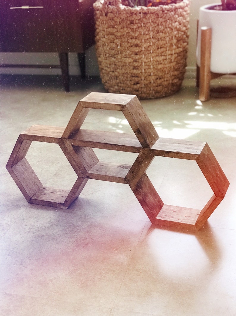 Puede incluir: Una estanter&iacute;a hexagonal de madera con tres niveles. La estanter&iacute;a est&aacute; hecha de madera natural con un acabado r&uacute;stico.