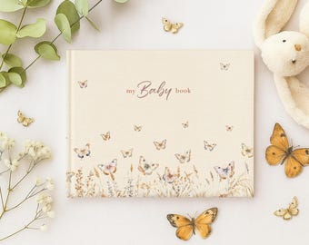 May include: A cream-colored baby book with the words "my Baby book" and butterfly illustrations. The book is surrounded by decorative butterflies, flowers, and a stuffed animal.