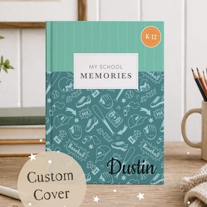 May include: A personalized school memory book with a teal cover featuring baseball-themed illustrations. The book has the text "My School Memories" and "Dustin" on the cover, with a "K-12" sticker. A "Custom Cover" sticker is also visible.