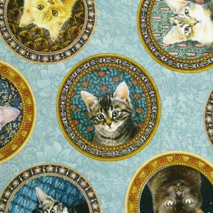 Op de afbeelding: Een blauwe stof met een herhalend patroon van katten in sierlijke gouden frames. Elke kat staat in een andere pose en heeft een uniek ontwerp.