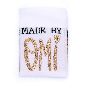 May include: White fabric label with black text "MADE BY" and gold glitter text "OMI" with a small gold heart.