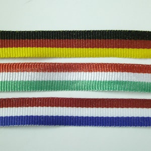 May include: Three different ribbon trims with the colours of the flags of Germany, Hungary, and the Netherlands. The German ribbon is black, red, and yellow. The Hungarian ribbon is red, white, and green. The Dutch ribbon is red, white, and blue.