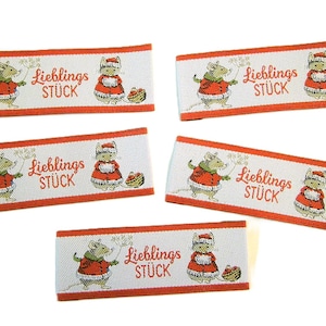 May include: Five rectangular fabric labels with a white background and red trim. Each label features a cartoon mouse and a mouse wearing a Santa hat, along with the German text "Lieblings STÜCK".