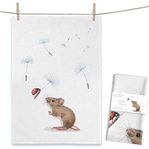 Könnte beinhalten: Ein weißes Geschirrtuch mit einer Aquarellillustration einer braunen Maus, die zu einem Marienkäfer auf einem Löwenzahnsamen aufschaut. Mehrere weitere Löwenzahnsamen schweben in der Luft. Eine gefaltete Version trägt eine Banderole mit dem Text Lucky Mouse.
