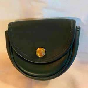 May include: A dark green leather purse with a gold button closure. The purse is shaped like a half-circle and has a flap that folds over the top.