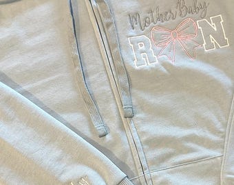 Mother Baby Embroidered Nurse zippered jacket. RN and Pink bow adorn this Personalized Sweat jacket. Includes name on sleeve. Custom Options