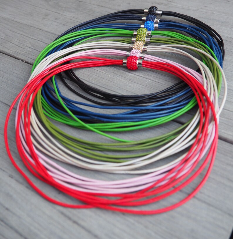 Pu&ograve; includere: Un set di collane in cordoncino di pelle di diversi colori con chiusure magnetiche. I cordoncini sono rossi, rosa, bianchi, verdi, blu, neri e altro ancora. Ogni cordoncino ha una perla di cristallo di colore diverso sulla chiusura.
