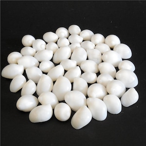 May include: A collection of smooth, white, oval-shaped stones. The stones vary in size and are arranged on a black surface. The polished stones have a glossy appearance, reflecting light. The overall aesthetic is clean and minimalist.