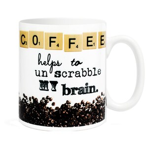 May include: White ceramic coffee mug with a brown and black coffee bean design. The mug has the text "C. O, F. F. E. E" in Scrabble tiles and the text "helps to un scrabble MY brain."