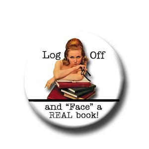 May include: A white button with a black border and text that reads "Log Off and "Face" a REAL book!"  A woman with red hair is leaning on a stack of books.