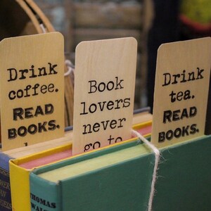 May include: Three wooden bookmarks with black text. The bookmarks read "Drink coffee. READ BOOKS.", "Book lovers never go to", and "Drink tea. READ BOOKS."