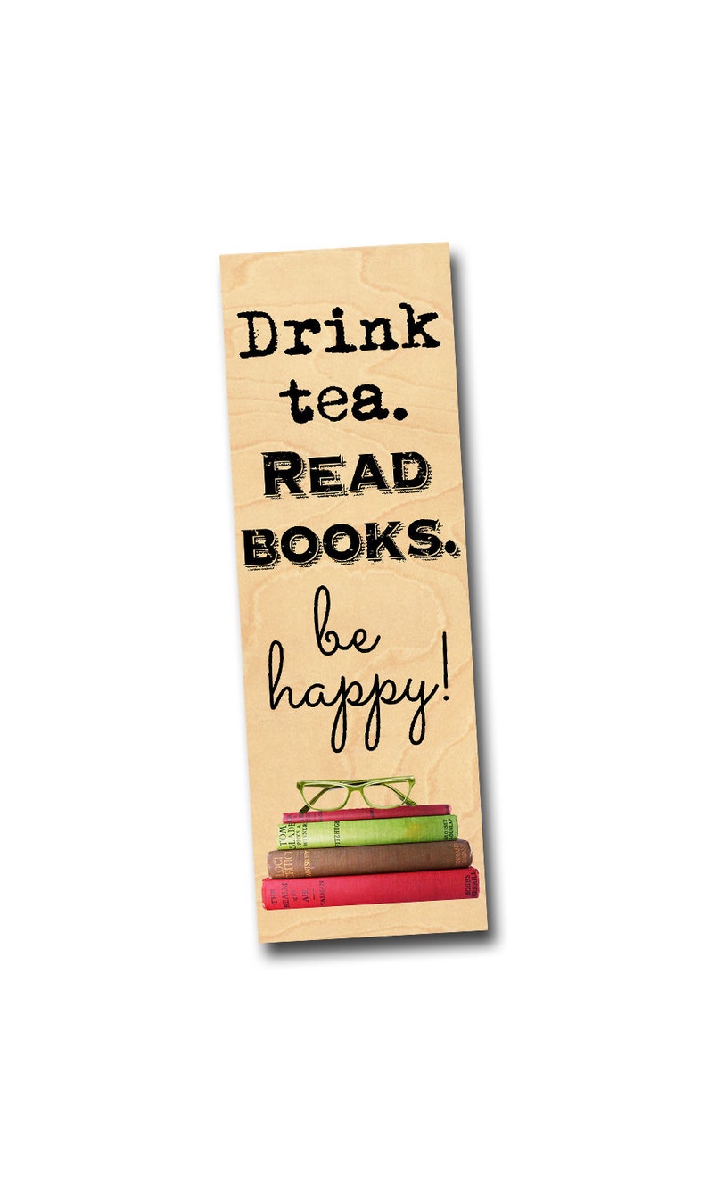 K&ouml;nnte beinhalten: Holz-Lesezeichen mit dem Text "Drink tea. READ BOOKS. be happy!" und einem Stapel B&uuml;cher und Brillen darauf.