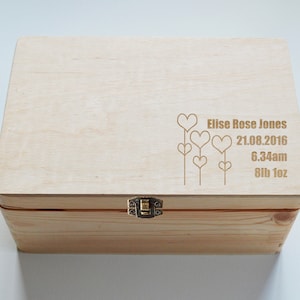 May include: A wooden keepsake box with a hinged lid and a brass latch. The lid is engraved with a design of hearts on stems and the text "Elise Rose Jones 21.08.2016 6.34am 8lb 1oz".