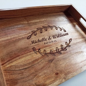 May include: A wooden serving tray with a personalised inscription that reads "Michelle & William Est 12.6.23" surrounded by a leafy wreath design.