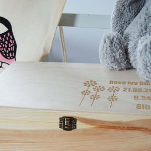 May include: A light wood keepsake box with a brass latch. The lid is engraved with a floral design and the text "Rose Ivy Smith 21.08.2016 6.34am 8lb 1oz".