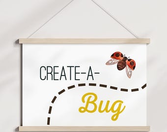 May include: A white poster with the words "CREATE-A-Bug" in black and yellow, featuring a dotted line and a ladybug illustration. The poster is suspended by a wooden frame and a string.