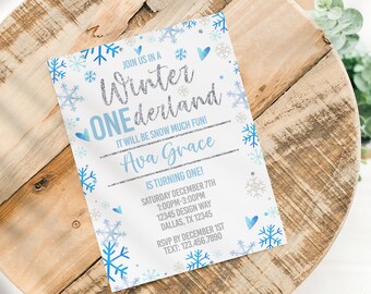 May include: A white invitation with blue snowflakes and hearts. The text reads "Join us in a Winter Wonderland One-derland. It will be snow much fun! Ava Grace is turning one! Saturday December 7th 1:00PM-3:00PM 12345 Design Way Dallas, TX 12345 RSVP by December 1st Text: 123.456.7890"