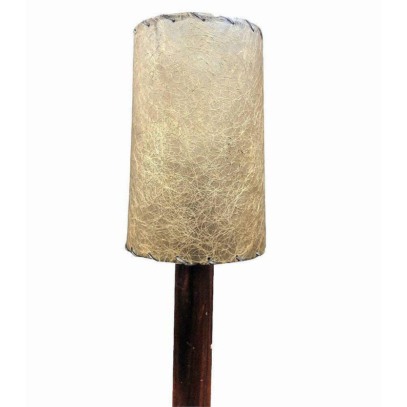 May include: A mid-century modern table lamp with a brown wooden base and a white, textured, drum-shaped lampshade.