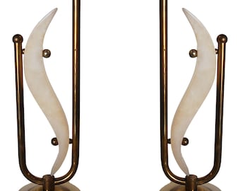 May include: A pair of brass and alabaster lamps with a unique crescent moon design. The lamps have a gold finish and a white alabaster base.