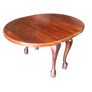 May include: A dark wood oval drop leaf table with four turned legs. The table is closed and ready for use.