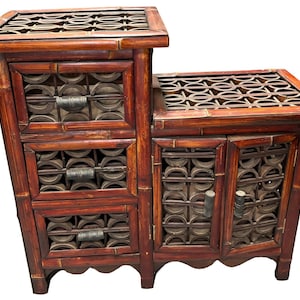 May include: A dark brown wooden cabinet with three drawers and two doors. The cabinet has a decorative lattice design on the front and is made of bamboo.