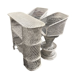 May include: A set of three white wicker bar stools and a matching bar table with a shelf. The bar stools have a unique, swirling design and the bar table has a rectangular top.