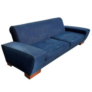 May include: A blue velvet sofa with wooden legs. The sofa has two cushions and a tufted back.