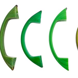 May include: Five curved, arch-shaped handles arranged in a row. The handles vary in shades of green, ranging from light lime to a vibrant, saturated emerald green. Each handle features a smooth, solid construction with visible mounting points.